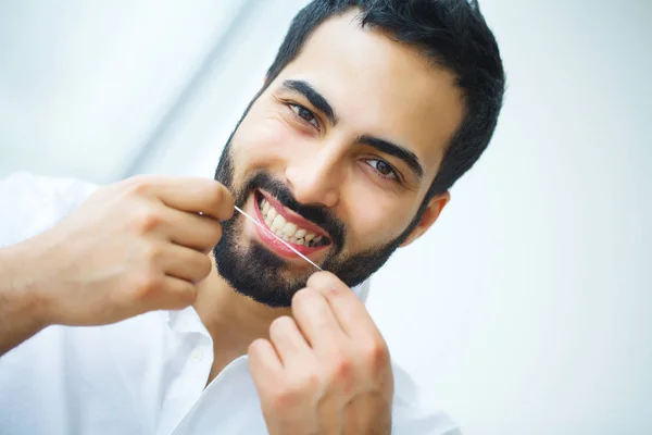 Teeth Care. Beautiful Smiling Man Flossing Healthy White Teeth.