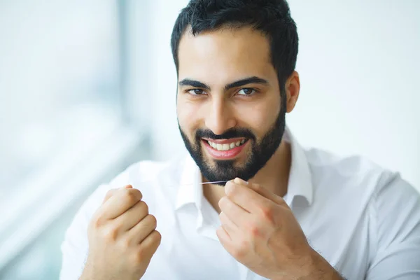 Teeth Care. Beautiful Smiling Man Flossing Healthy White Teeth. Stock Image