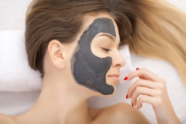 Spa therapy for young woman having facial mask at beauty salon -