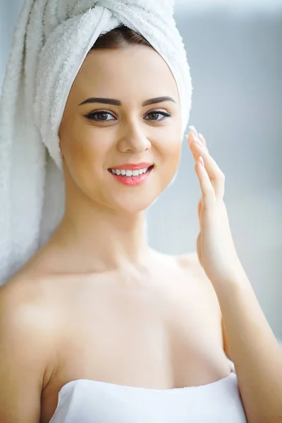 Muchacha atractiva poniendo crema anti-envejecimiento en su cara —  Fotos de Stock