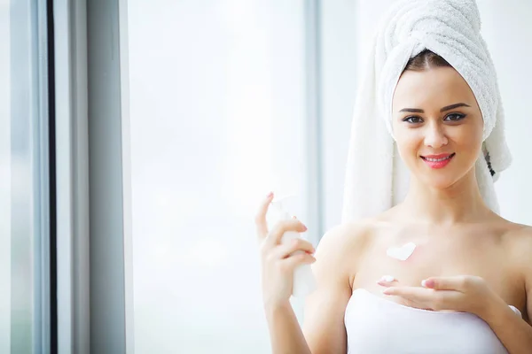 Muchacha atractiva poniendo crema anti-envejecimiento en su cara — Foto de Stock