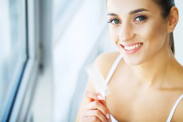 Tandblekning. Vackra leende kvinna som håller tandblekning Strip — Stockfoto