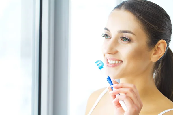 Красива усміхнена жінка чистить здорові білі зуби пензлем . — стокове фото