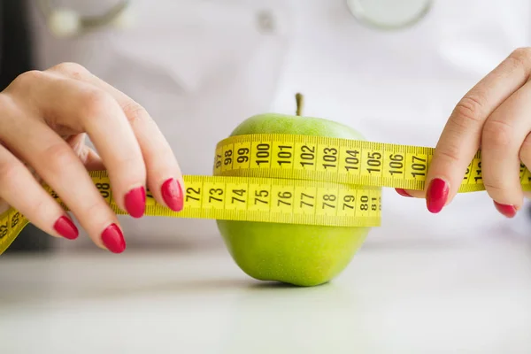 Dieta. Mujer sosteniendo una manzana verde y midiendo —  Fotos de Stock
