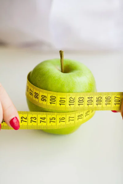 Diet. Woman holding a green apple and measuring