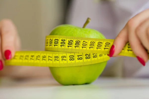 Dieta. Mujer sosteniendo una manzana verde y midiendo —  Fotos de Stock