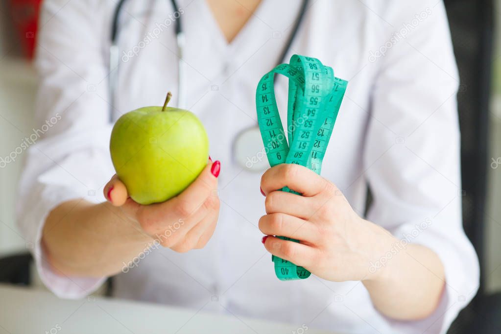 Diet. Female Nutritionist and Holding an Apple and a Measure Tap