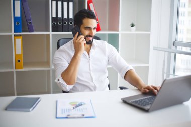 Neşeli genç yakışıklı modern yönetmen h bir dizüstü bilgisayar üzerinde çalışan