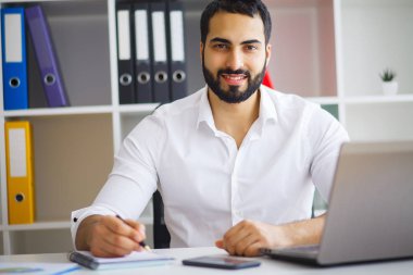 Masada oturan ve dizüstü kullanarak genç yakışıklı girişimci 