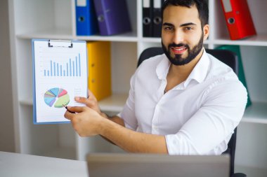 Masada oturan ve dizüstü kullanarak genç yakışıklı girişimci 