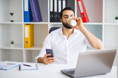 Masada oturan ve dizüstü kullanarak genç yakışıklı girişimci 