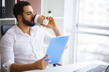 Masada oturan ve dizüstü kullanarak genç yakışıklı girişimci 