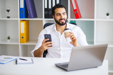 Masada oturan ve dizüstü kullanarak genç yakışıklı girişimci 