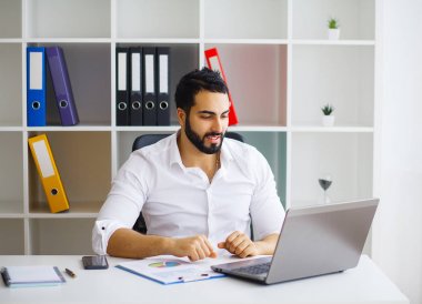 Neşeli genç yakışıklı modern yönetmen h bir dizüstü bilgisayar üzerinde çalışan