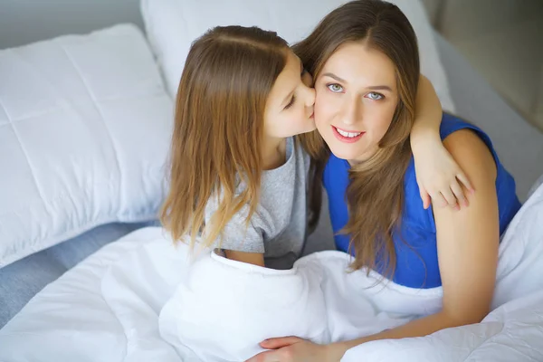 ベッドに小さな女の子と遊ぶ若い女性 — ストック写真