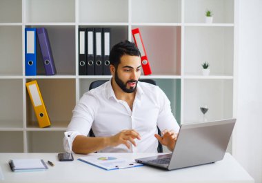 Masada oturan ve dizüstü kullanarak genç yakışıklı girişimci 