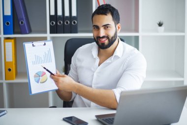 Ofisteki bilgisayarını kullanarak gülümseyen iş adamı.