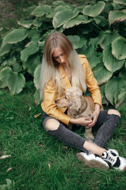 Gürültü ve klasik tarz. Köpekli genç kız parkta yürüyor ve güzel yaz gününün tadını çıkarıyor.