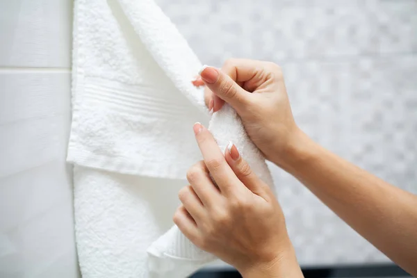 Fermer les mains utiliser une serviette blanche dans la salle de bain légère — Photo