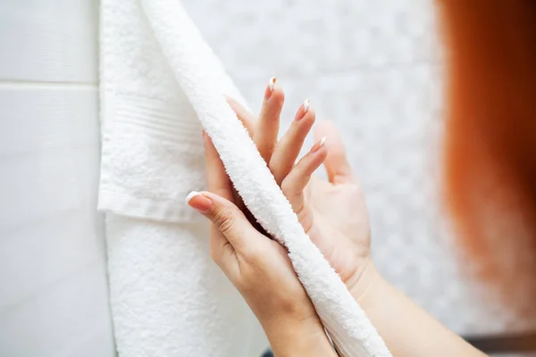 Fermer les mains utiliser une serviette blanche dans la salle de bain légère — Photo