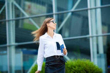 Tatil. Gülümseyen kadın yolcu havaalanı yolcu salonundan bavulçekerek kapıdan çıkışa doğru ilerliyor.