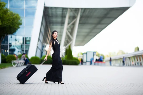 Vakantie. Lachende vrouwelijke passagier die doorgaat met het verlaten van de Gate Trek koffer via de luchthaven Concourse. — Stockfoto