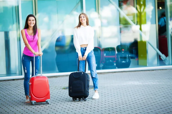 一緒に海外旅行、空港でスーツケースの荷物を運ぶ 2 つの幸せな女の子. — ストック写真