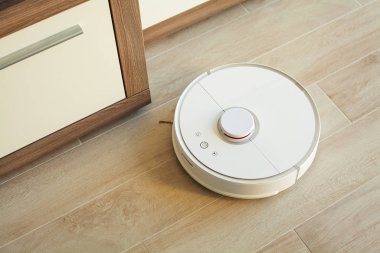 Akıllı Ev. Elektrikli süpürge robotu oturma odasında ahşap zeminde koşar.
