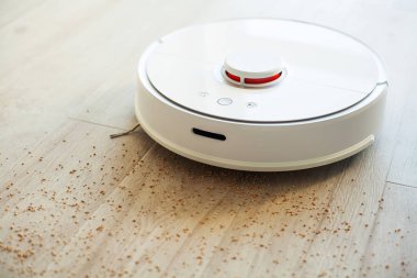 Akıllı Ev. Elektrikli süpürge robotu oturma odasında ahşap zeminde koşar.