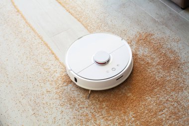Akıllı Ev. Elektrikli süpürge robotu oturma odasında ahşap zeminde koşar.