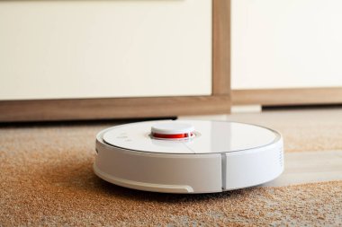 Akıllı Ev. Elektrikli süpürge robotu oturma odasında ahşap zeminde koşar.