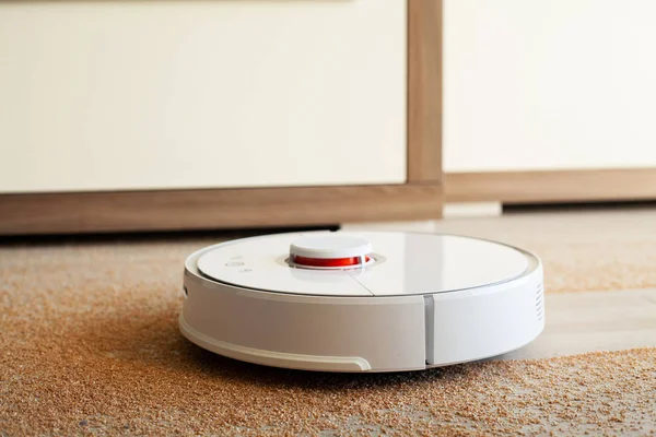 Akıllı Ev. Elektrikli süpürge robotu oturma odasında ahşap zeminde koşar.