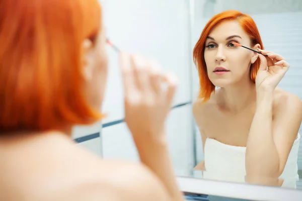 Menina bonita aplica cosméticos no rosto no banheiro leve . — Fotografia de Stock