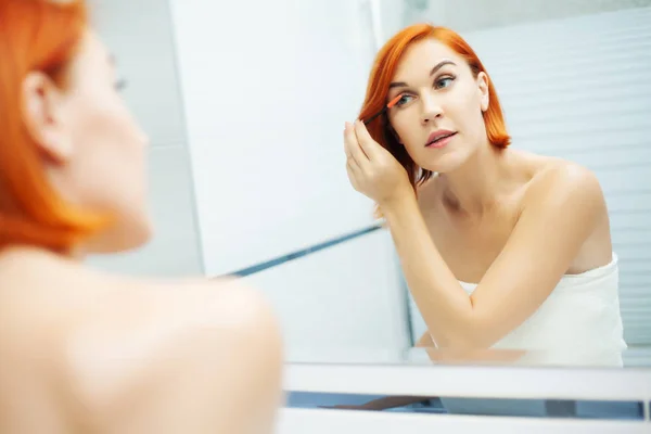 Menina bonita aplica cosméticos no rosto no banheiro leve . — Fotografia de Stock