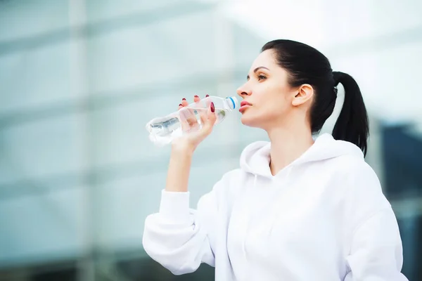 Deportes al aire libre. Mujer bebiendo agua después de correr — Foto de Stock