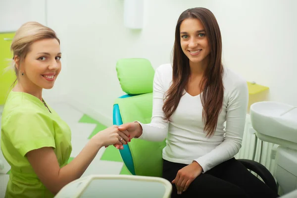 Dentista en el consultorio dental hablando con la paciente femenina y preparándose para el tratamiento — Foto de Stock