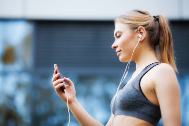 Fitness. Güzel kadın su içme ve koştuktan sonra müzik dinlemek