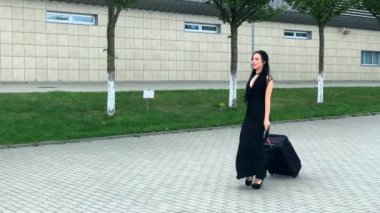 Tatil. Gülümseyen kadın yolcu havaalanı yolcu salonundan bavulçekerek kapıdan çıkışa doğru ilerliyor