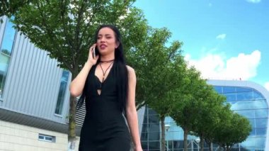 Havaalanındaki iş kadını havaalanında el bagajıyla yürürken akıllı telefondan konuşuyor. Sohbet için cep telefonu kullanan kız