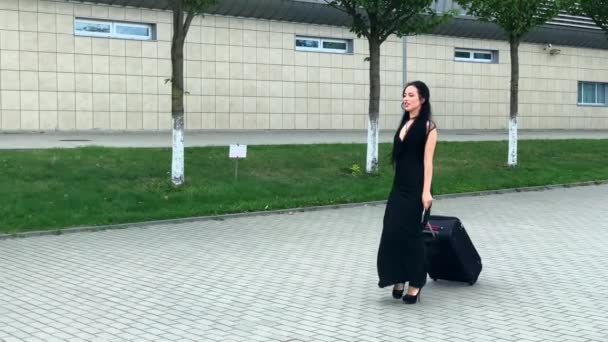 Des vacances. Passagère souriante se dirigeant vers la porte de sortie tirant sa valise dans le hall de l'aéroport — Video
