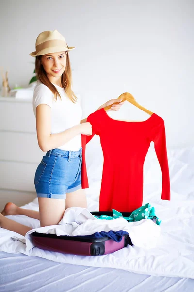 Mulher bonita recolhe roupas em mala de viagem em uma viagem — Fotografia de Stock