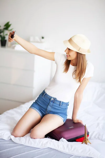 Beautiful woman collects clothes in travel suitcase on a trip — 스톡 사진