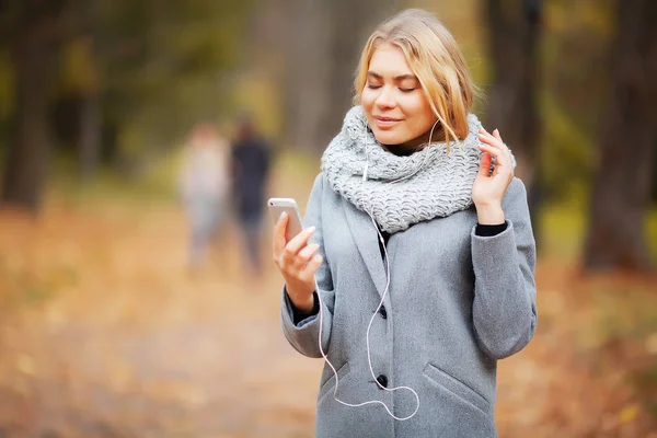 Young Beauty woman listening music in autumn forest — Stock Photo, Image