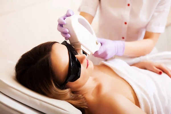 Esteticista dando tratamiento de la acumulación del laser a la cara joven de las mujeres en la clínica de la belleza . —  Fotos de Stock