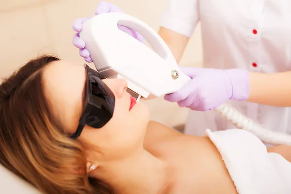 Esteticista dando tratamiento de la acumulación del laser a la cara joven de las mujeres en la clínica de la belleza . — Foto de Stock