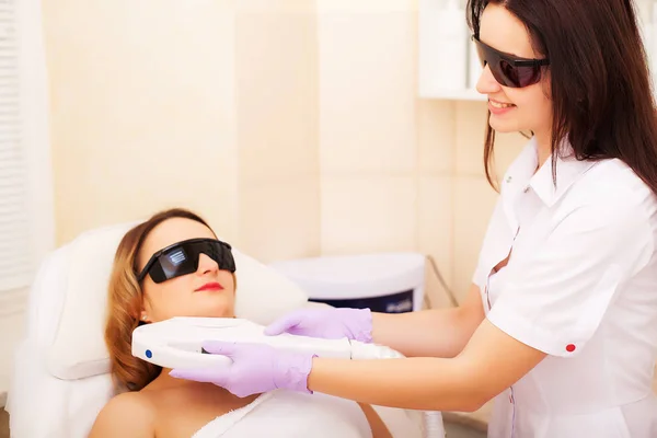 Beautician dając zabieg depilacji laserowej do młodych kobiet twarz w Beauty Clinic. — Zdjęcie stockowe
