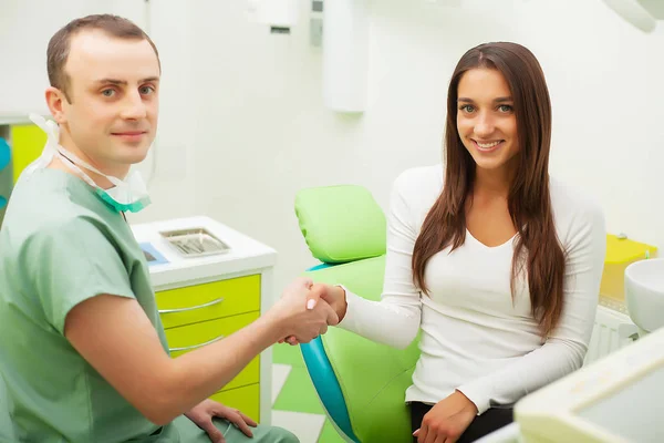 Dentista em consultório odontológico conversando com paciente do sexo feminino e se preparando para o tratamento — Fotografia de Stock