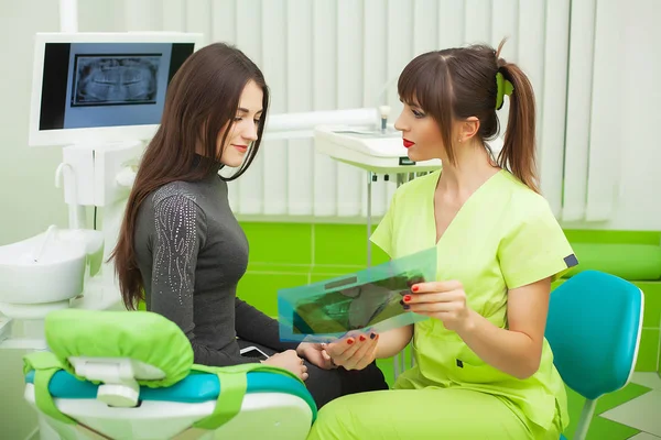 Dentista em consultório odontológico conversando com paciente do sexo feminino e se preparando para o tratamento — Fotografia de Stock