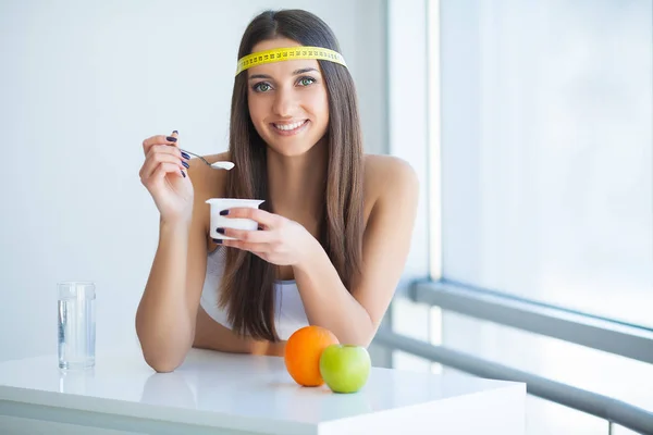 Szczęśliwa młoda kobieta jedzenie jogurt w kuchni — Zdjęcie stockowe