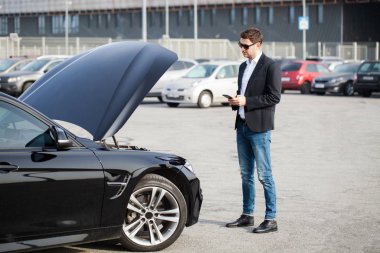 Yolun ortasında kırık arabalı bir adam var.